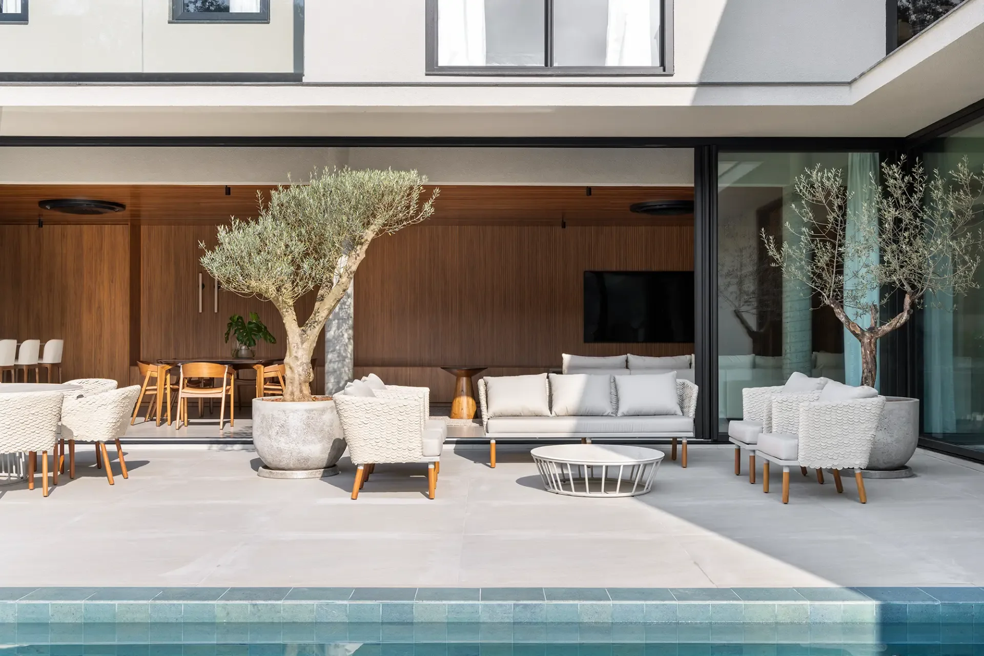 Área externa com sofás, poltronas e piscina